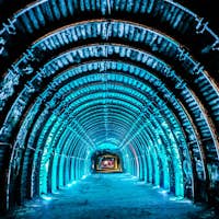 Túnel iluminado con una serie de costillas arqueadas iluminadas en azul que se extienden en la distancia, creando una sensación de profundidad y estructura.